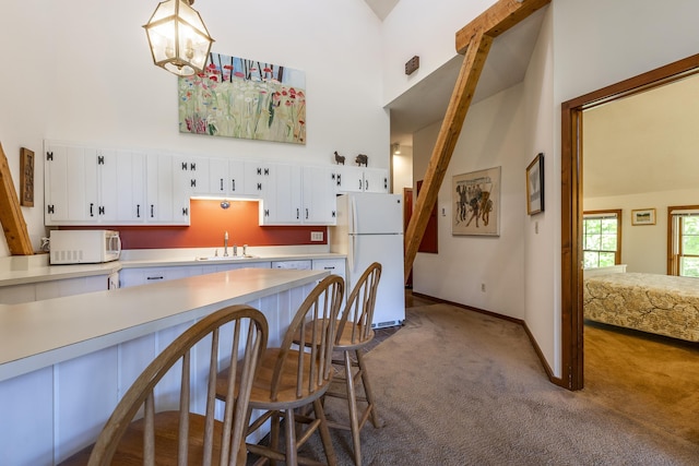 27 Lawrence Hill Rd Unit 5, Weston, VT 05161 - kitchen featuring white appliances, high vaulted ceiling, dark colored carpet, light countertops, and a kitchen bar