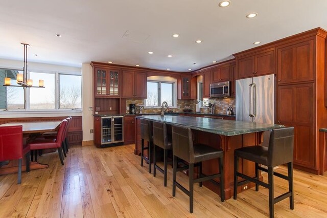 kitchen with stainless steel appliances, hanging light fixtures, light hardwood / wood-style floors, and a healthy amount of sunlight