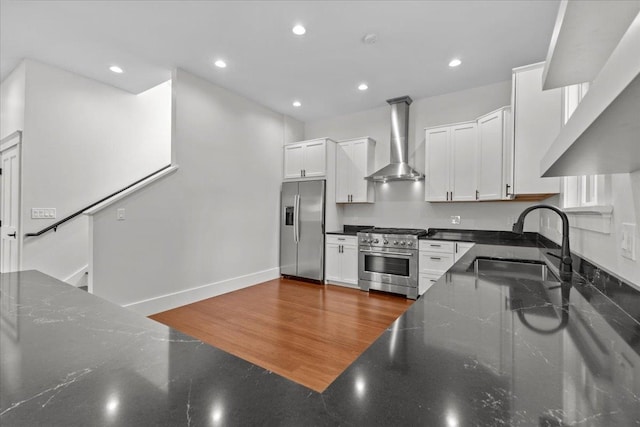 kitchen featuring wall chimney exhaust hood, white cabinets, and appliances with stainless steel finishes