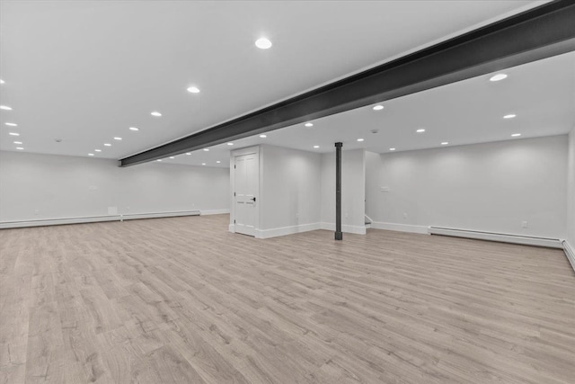 basement featuring light wood-type flooring and a baseboard heating unit