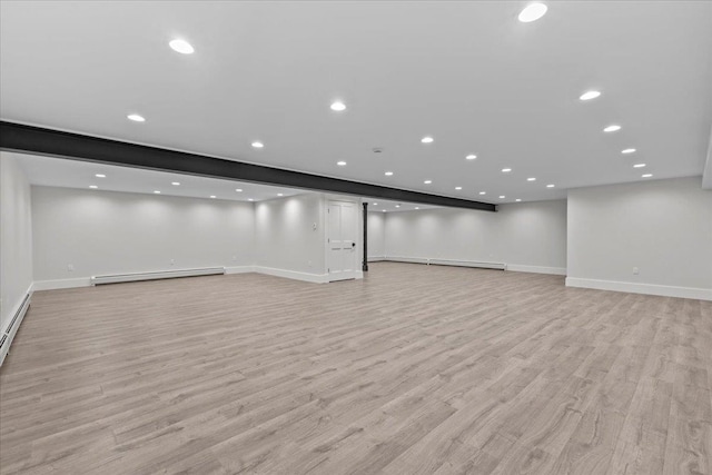 basement featuring light hardwood / wood-style flooring and baseboard heating