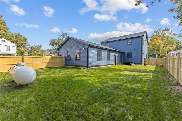 back of property with a fenced backyard and a lawn
