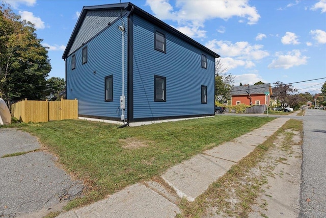 view of side of home with fence and a yard