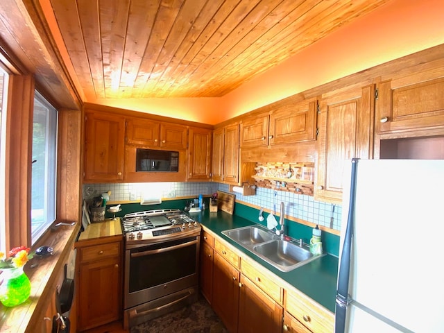 kitchen with lofted ceiling, sink, gas range, white fridge, and decorative backsplash