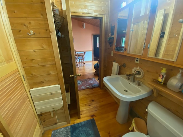 bathroom with wood walls, hardwood / wood-style flooring, and toilet