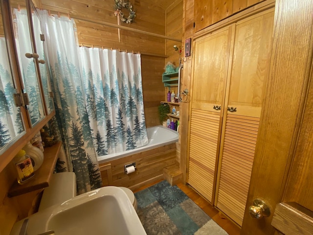 full bathroom with shower / bath combination with curtain, toilet, wooden walls, hardwood / wood-style floors, and sink