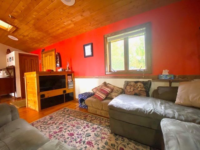 living room featuring vaulted ceiling with skylight, light wood-type flooring, and wood ceiling