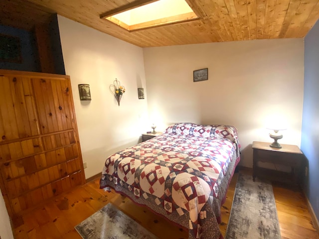 bedroom featuring hardwood / wood-style floors, wooden ceiling, and lofted ceiling with skylight