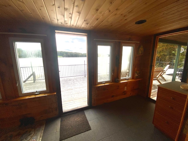 entryway with wood ceiling, a water view, and wooden walls