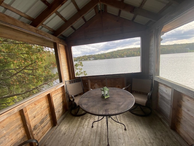 sunroom featuring a healthy amount of sunlight, vaulted ceiling with beams, and a water view