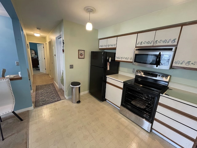 kitchen with pendant lighting, black refrigerator, white cabinets, and electric range