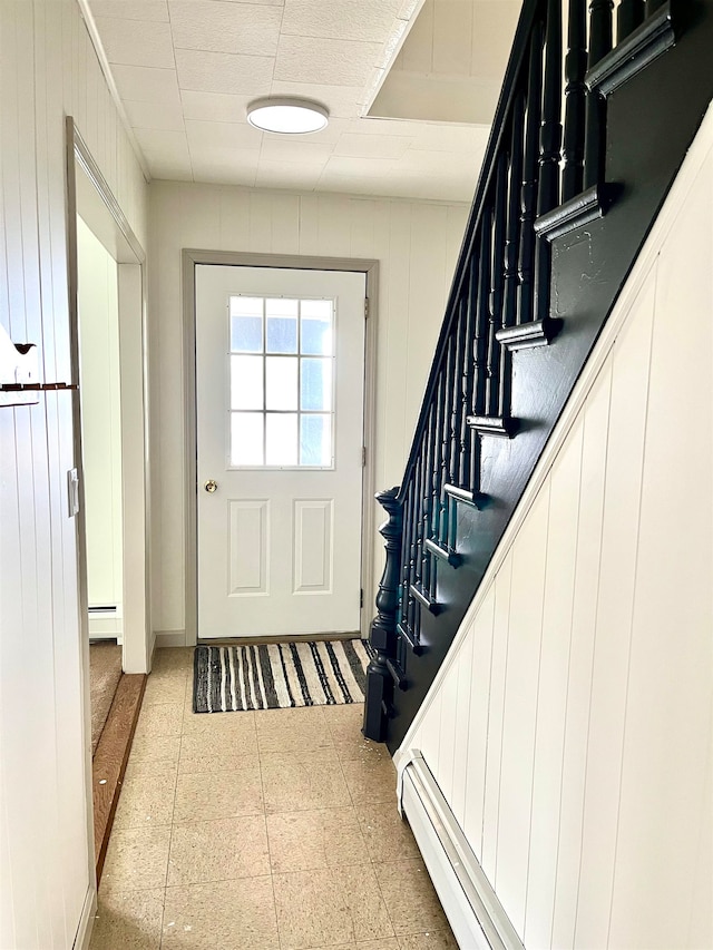 doorway to outside featuring a baseboard radiator and wooden walls