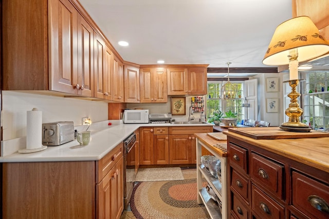 kitchen with sink, dishwasher, hanging light fixtures, and wooden counters