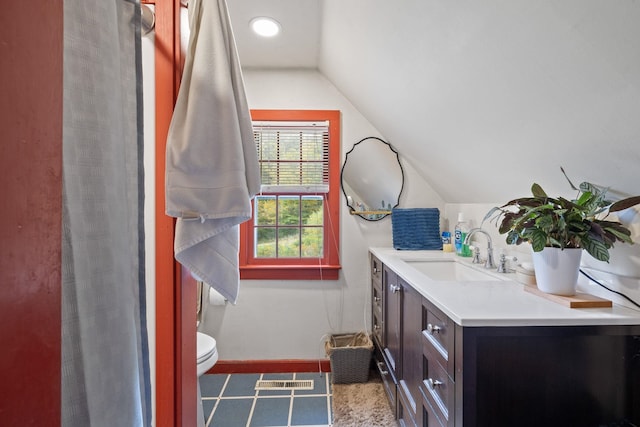 bathroom featuring vanity, toilet, and vaulted ceiling