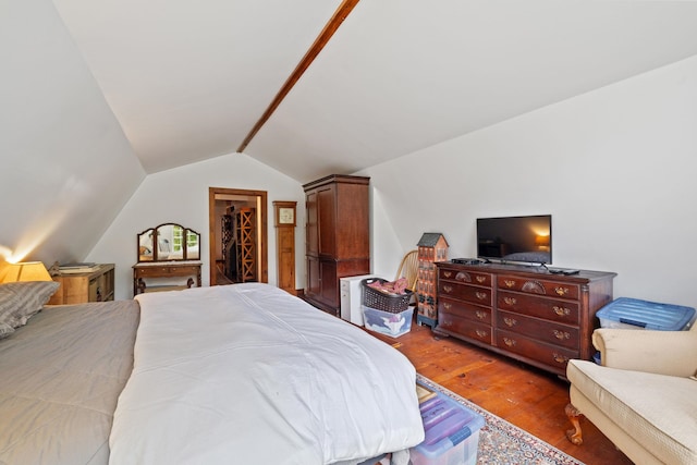 bedroom featuring a spacious closet, lofted ceiling, a closet, and hardwood / wood-style flooring