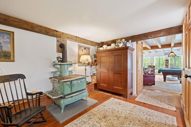 living area featuring pool table, light hardwood / wood-style floors, and a wood stove