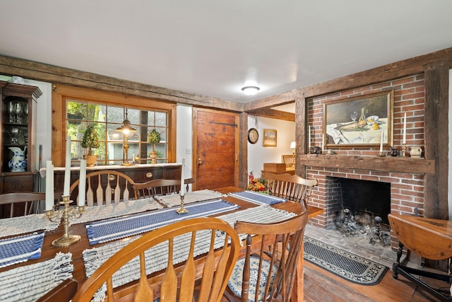 dining room featuring hardwood / wood-style flooring and a brick fireplace