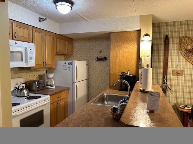 kitchen with a textured ceiling, white appliances, and sink