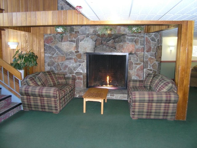 living room featuring carpet floors, a fireplace, and wood walls