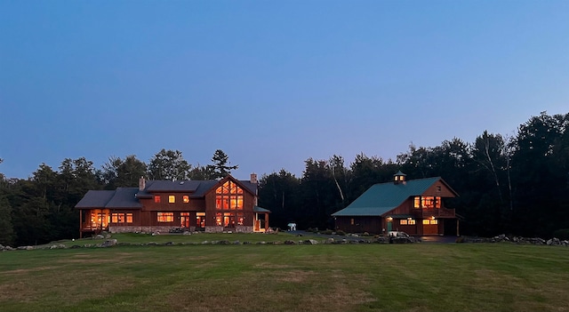 back house at dusk with a lawn