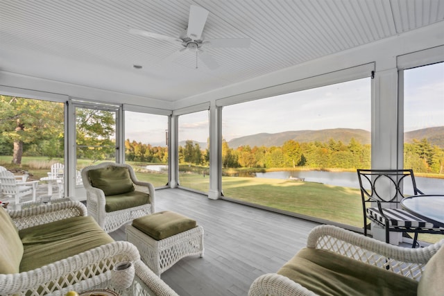 sunroom / solarium with a water and mountain view and ceiling fan