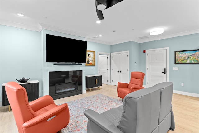 living room featuring ceiling fan, crown molding, and light hardwood / wood-style floors