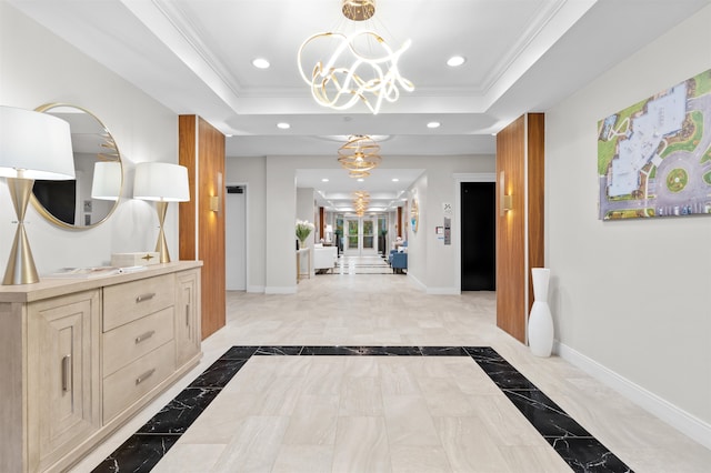 hall featuring an inviting chandelier, a tray ceiling, and crown molding