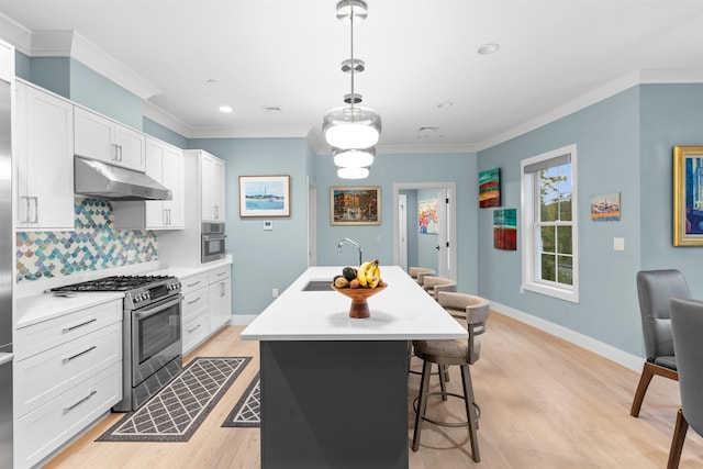 kitchen featuring white cabinetry, stainless steel appliances, light hardwood / wood-style flooring, decorative light fixtures, and a kitchen island with sink