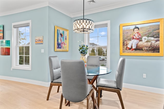 dining area with light wood-type flooring, crown molding, and a chandelier