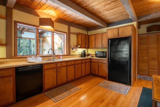 kitchen featuring beamed ceiling, light wood-type flooring, sink, and black appliances