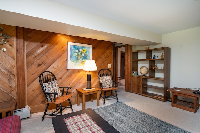 sitting room with light carpet, a baseboard heating unit, and wood walls