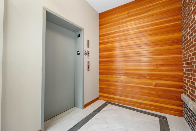 corridor featuring brick wall, wooden walls, and elevator