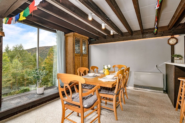 carpeted dining room with beamed ceiling