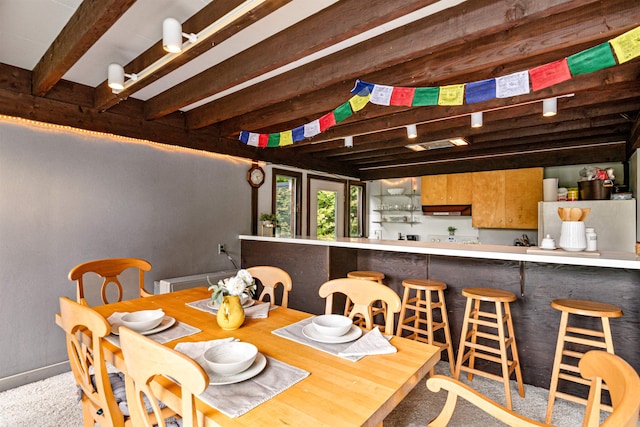 dining room featuring light carpet and beam ceiling