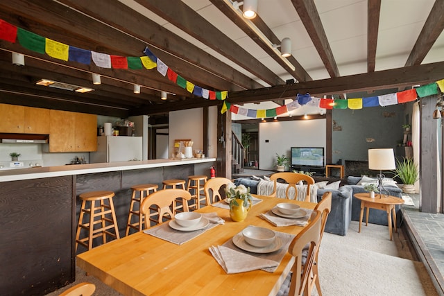 carpeted dining area with beam ceiling