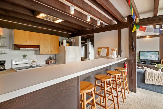 kitchen featuring range, a kitchen bar, beam ceiling, and white fridge