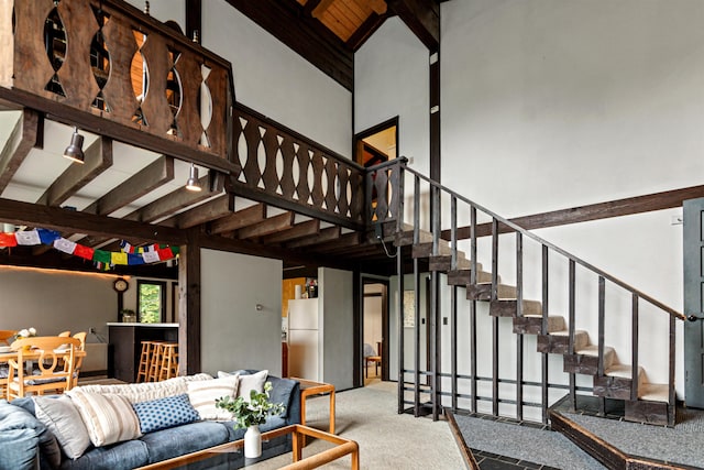 stairs featuring beam ceiling and a high ceiling