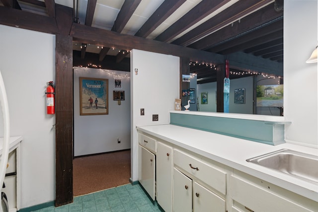 kitchen with beam ceiling, sink, and white cabinets