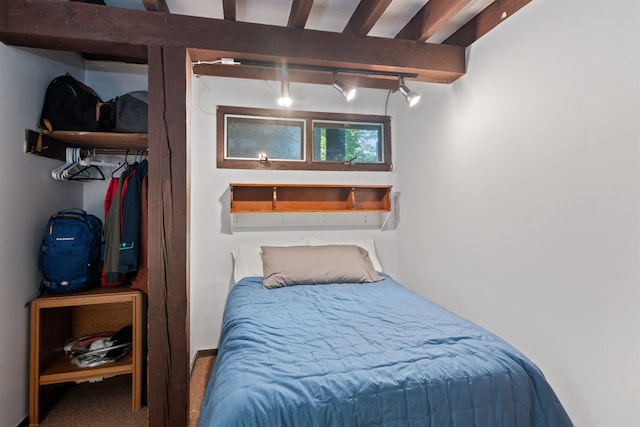 carpeted bedroom with beam ceiling and rail lighting