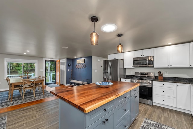 kitchen featuring hanging light fixtures, white cabinetry, butcher block counters, stainless steel appliances, and dark hardwood / wood-style floors