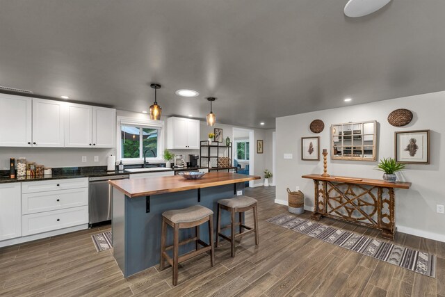 kitchen featuring hanging light fixtures, dark wood-type flooring, white cabinets, dishwasher, and sink