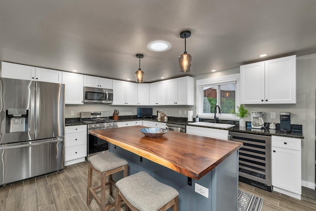 kitchen featuring butcher block counters, beverage cooler, pendant lighting, and stainless steel appliances