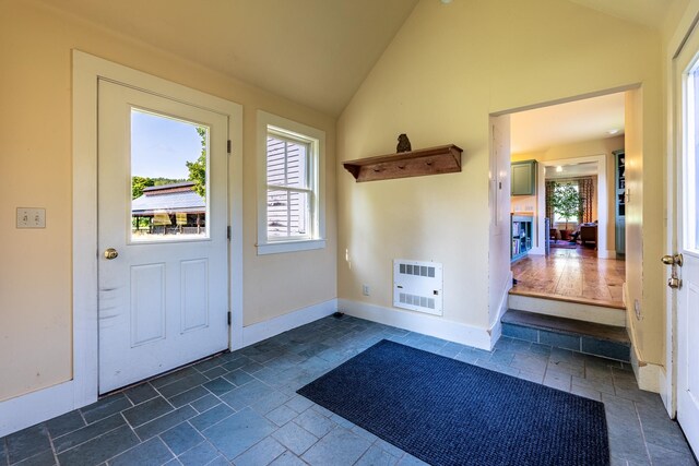 entryway featuring heating unit, a fireplace, and high vaulted ceiling