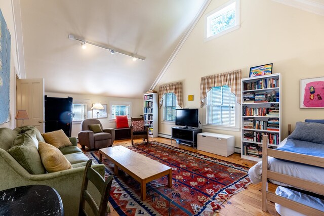 living room with rail lighting, high vaulted ceiling, baseboard heating, hardwood / wood-style floors, and ornamental molding