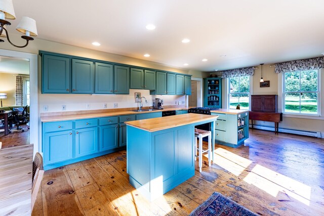 kitchen featuring wooden counters, light hardwood / wood-style flooring, baseboard heating, a center island, and a notable chandelier