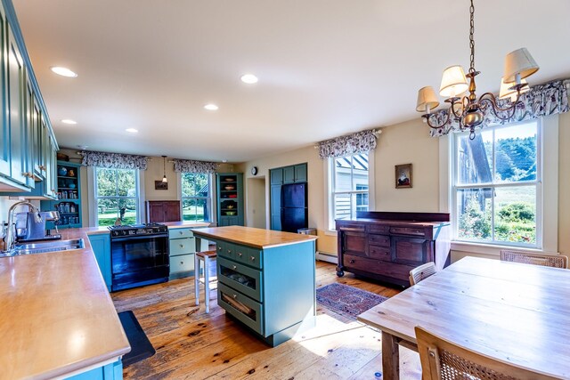 kitchen featuring black range oven, a wealth of natural light, a center island, and sink