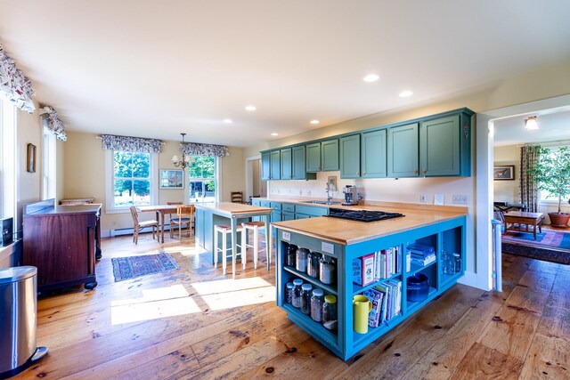 kitchen with pendant lighting, a breakfast bar, light hardwood / wood-style floors, sink, and butcher block countertops