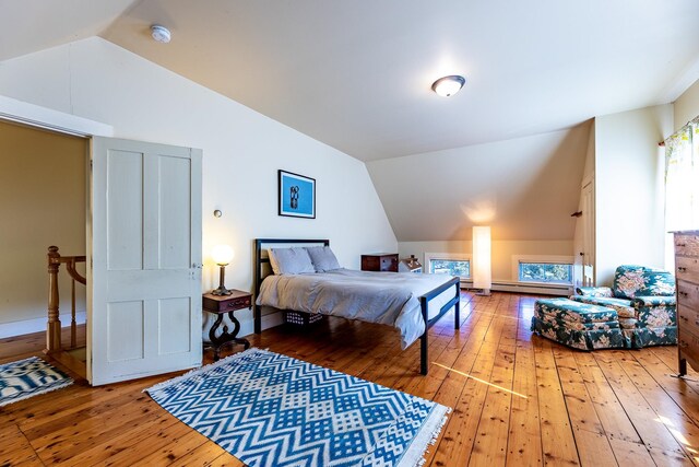 bedroom with a baseboard heating unit, vaulted ceiling, and hardwood / wood-style flooring