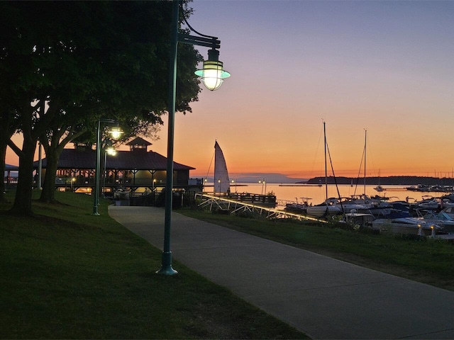 surrounding community with a water view and a lawn