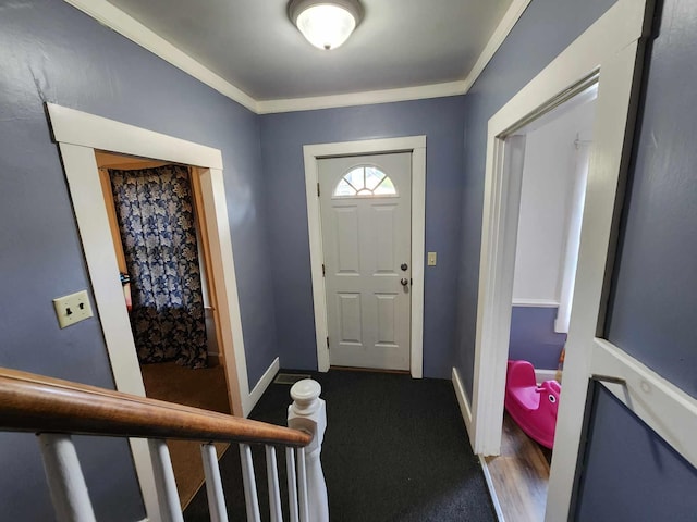 entrance foyer featuring baseboards, ornamental molding, and carpet floors